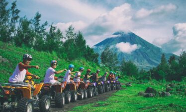 Group of friends enjoying an ATV ride with Mayon Volcano in the background.